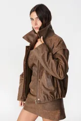 Campera de cuero estilo bomber con acabado desgastado, cuello clásico, cierre frontal oculto y mangas desmontables que permiten convertirla en chaleco.