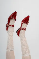 Chatas rojas de charol con punta fina y tiras con hebillas y ojalillos.