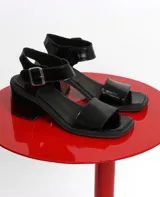 Sandalias negras de charol con taco bloque y pulsera al tobillo con hebilla metálica.