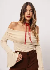 Blusa beige con hombros descubiertos, mangas largas acampanadas y confeccionada en tela stretch con lurex.
