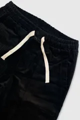 Pantalón de pana negro con cintura elástica y cordón de algodón. Cuenta con bolsillos laterales, un bolsillo trasero y el parche característico de Polonio.