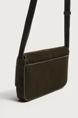 Bolso tipo bandolera de piel con acabado serraje, compartimento principal con cierre de solapa e imán, bolsillo posterior y asa de hombro ajustable.