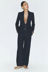 Blazer de cuello solapa y manga larga con cierre frontal de un botón. Presenta bolsillos delanteros con solapa y diseño estructurado.