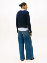 Sweater de punto color azul marino, con cuello en V ribeteado con dos franjas blancas. Presenta tejido trenzado (cableado) en el frente y puños y dobladillo acanalados.