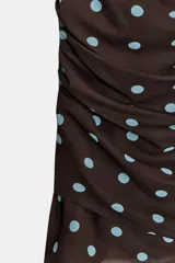 Vestido corto marrón con lunares celestes, escote fluido, tirantes finos ajustables y frunces en el delantero. Tiene forro interior y cierre lateral con cremallera oculta.