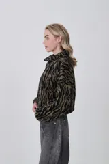 Campera de corderito con estampado animal print, de manga larga, cuello alto y cierre frontal completo.