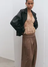 Pantalón balloon de tiro alto color marrón, confeccionado en algodón, con cintura ajustable con elástico, pinzas en la parte delantera, bolsillos laterales y bajos fruncidos con elástico.
