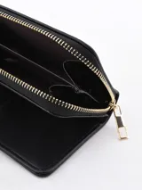 Billetera negra con cierre de cremallera y detalle de hebilla decorativa en color beige.