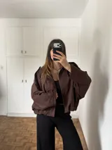 Campera de gamuza color chocolate, con corte oversize, cierre frontal y diseño de hombros caídos.