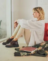 Botinetas de caña baja con suela track gruesa, combinando cuero negro en la puntera, gamuza marrón en el lateral y detalles de textura animal print tipo serpiente en tonos marrones. Presenta un cierre de solapa con velcro en el empeine.