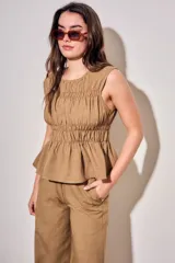 Blusa sin mangas de viscosa con estampado a cuadros vichy en tonos marrones y tostados, con doble fruncido elástico en el pecho y la cintura que genera un sutil vuelo inferior.