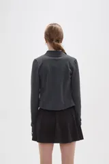 Campera deportiva de ajuste entallado, confeccionada en poliéster color gris oscuro. Presenta cuello alto, cierre frontal completo y mangas largas con aberturas para los pulgares.