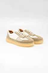 Zapatillas urbanas de cuero color beige, con detalles en blanco y suela de goma color caramelo.