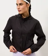 Campera rompevientos marrón de corte cropped, con capucha, cierre frontal de cremallera, cuello alto y puños elásticos.