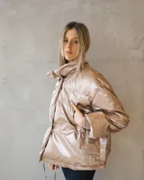 Campera puffer de corte oversize en tono champagne metalizado, con cuello alto envolvente y acabado brillante.