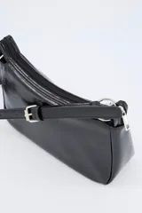 Bolso crossbody de efecto cuero en color negro, con diseño compacto, cierre superior y correa ajustable con hebilla metálica.
