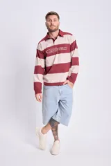 Remera tipo rugby de manga larga a rayas horizontales color bordó y beige, con cuello polo y cierre de dos botones. Estampa frontal con la leyenda "Race Team".