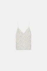Top de tul blanco con estampado de lunares negros, escote en V y tirantes finos ajustables.