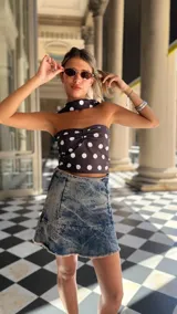 Top estilo pañuelo (bandana) de color marrón oscuro con estampado de lunares blancos. El diseño es strapless con un nudo central fruncido y se ata al cuello como un halter.