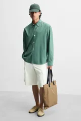 Bolso tipo shopper color beige, fabricado en tejido técnico con asas de mano de piel color negro. Tiene compartimento principal con cierre de imán y bolsillo interior con cremallera.