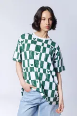 Remera de manga corta con estampado de cuadros verdes y blancos, con pequeños motivos de la silueta de Mickey Mouse dispersos por el diseño.