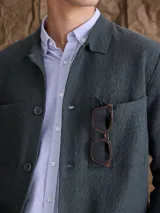 Overshirt de tejido de punto color azul marino, con cuello camisero, cierre frontal de botones y dos bolsillos frontales tipo parche.