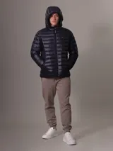Campera acolchada con capucha de Calvin Klein, color azul marino, con cierre frontal y bolsillos laterales con cremallera. Diseño ligero y funcional con logo de la marca en el pecho.