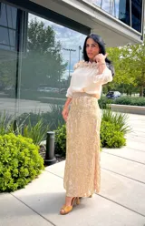 Falda larga color beige con sobrecapa de encaje dorado con diseño floral o arabesco.