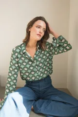 Camisa de manga larga con cuello camisero y cierre frontal de botones, confeccionada en tela estampada con un patrón geométrico de abanicos en tonos verdes y beige.