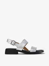 Sandalias plateadas de cuero vacuno con dos tiras anchas sobre el empeine, tira trasera con hebilla ajustable y suela negra con pequeño taco cuadrado.