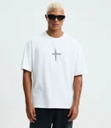 Remera blanca de algodón con modelado boxy, cuello redondo y manga corta. Presenta un estampado central en la parte delantera que forma una cruz con la palabra "MAYHEM" en el centro.