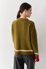 Buzo de lana con cuello redondo, mangas largas con diseño de ochos y puños con abertura para el pulgar. Presenta un diseño tricolor en bloques con franjas en tonos bordó, mostaza y beige.