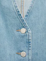 Chaleco de denim con cuello en V, cierre frontal con botones y lazo ajustable en la cintura. Presenta un diseño entallado con costuras verticales y bajo redondeado.