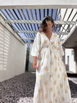 Túnica larga de color blanco con estampado de corales en color dorado. Presenta escote en V profundo, mangas tres cuartos amplias y ajuste en la cintura mediante cordón con borlas.