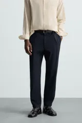 Pantalón chino de algodón color crema, corte regular fit, con cierre frontal de cremallera y botón, bolsillos delanteros y bolsillos traseros de vivo con botón.