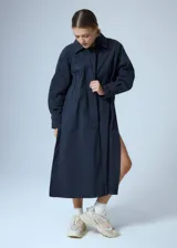 Trench midi negro confeccionado en algodón y nylon repelente al agua, con cuello clásico, cierre cruzado con botones, cinturón ajustable, mangas largas con puños abotonados, bolsillos internos altos y tajos laterales.