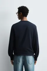 Jersey de punto color azul marino, con cuello redondo y manga larga. Presenta acabados en rib en cuello, puños y bajo.