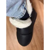 Pantuflas botitas color tostado con diseño acolchado y plataforma, forradas con corderito sintético blanco en el interior y el cuello. Cuentan con una pequeña etiqueta decorativa en el lateral.