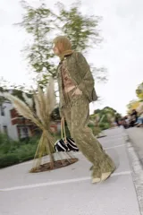 Pantalón de jean color verde oliva con efecto desgastado y textura rústica. Presenta un corte holgado con detalles de cintas ajustables en los tobillos que crean un efecto fruncido.