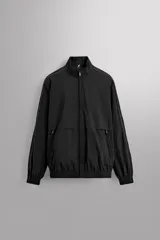 Chaqueta negra regular fit, confeccionada en tejido técnico con algodón. Presenta cuello subido, manga larga, forro interior de red y abertura en la espalda para transpiración. Incluye bolsillos con cierre de cremallera en la cadera, acabados elásticos y cierre frontal con cremallera.