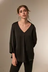 Blusa de satén color bordó con cuello en V y mangas tres cuartos. Presenta un diseño holgado con un pliegue central en el frente.