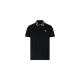 Chomba negra de manga corta con cierre frontal de tres botones, cuello con diseño geométrico Greca en tonos beige y negro, y detalle de Medusa bordada en el pecho.
