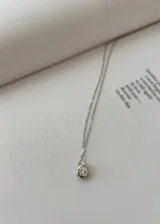 Collar plateado con dije circular con un cristal incrustado.