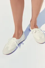 Zapato tipo blucher blanco con puntera y talón en gamuza gris claro, con cordones y suela plana color caramelo.