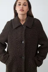 Tapado largo de textura tipo shearling con acabado volumétrico y cálido. Presenta cuello camisero, cierre frontal con botones y un calce relajado.