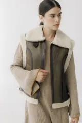 Chaleco de cuero color chocolate con interior y bordes de piel sintética en color crema. Presenta cierre frontal y costuras reforzadas en contraste.