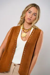 Chaleco marrón de cuero descarne con terminación en picos, tachas metálicas y flecos en la espalda.