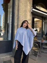 Poncho de hilo liviano en color celeste, con cuello alto y diseño de caída fluida y holgada.