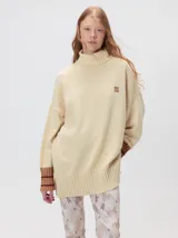 Pullover de cuello tortuga color marrón, de corte holgado y diseño básico. Presenta puños acanalados en contraste de color bordó con líneas horizontales celestes.