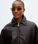 Campera de cuero sintético con diseño balonê, cuello camisero, cierre frontal con cremallera, mangas largas y ruedo elástico.